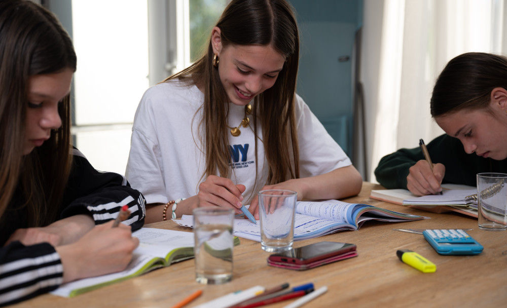 Drie jongeren maken huiswerk aan de keukentafel